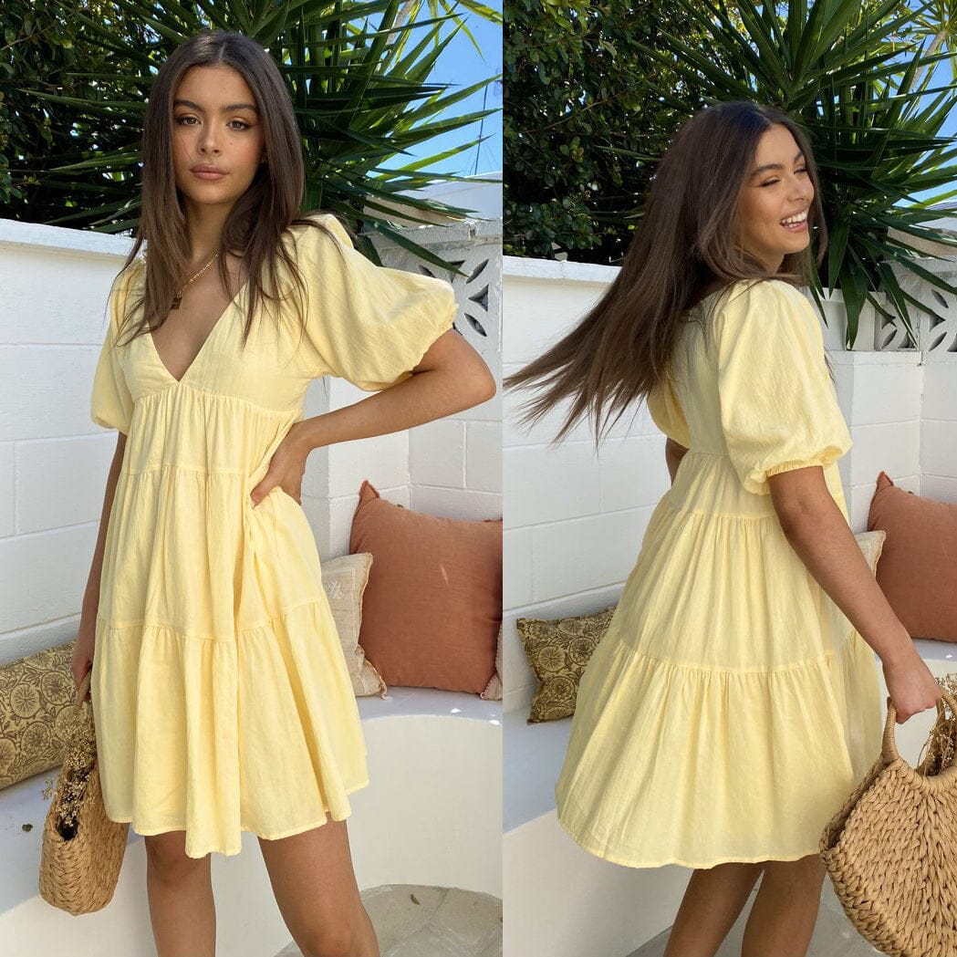 jeune femme portant une robe jaune à manches bouffantes, modèle hermine, en extérieur sur une terrasse ensoleillée