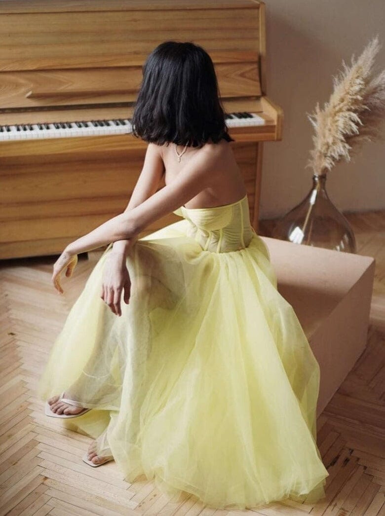 jeune femme assise près d'un piano en robe longue tulle ludivine jaune clair, ambiance élégante et décontractée