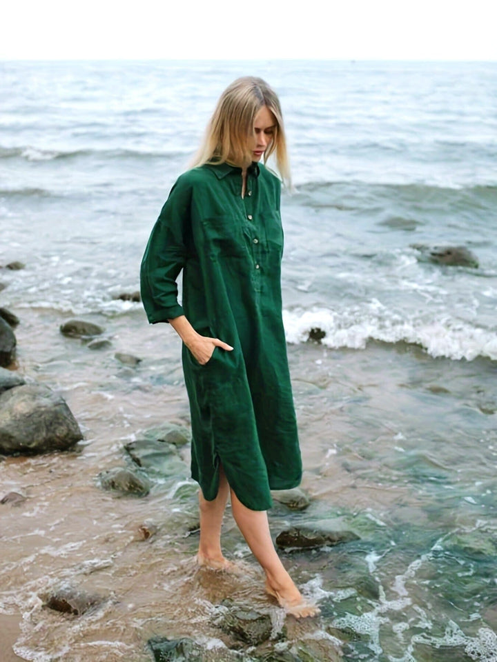 Femme marchant sur la plage en longue robe chemise verte, style décontracté et élégant pour l'été.