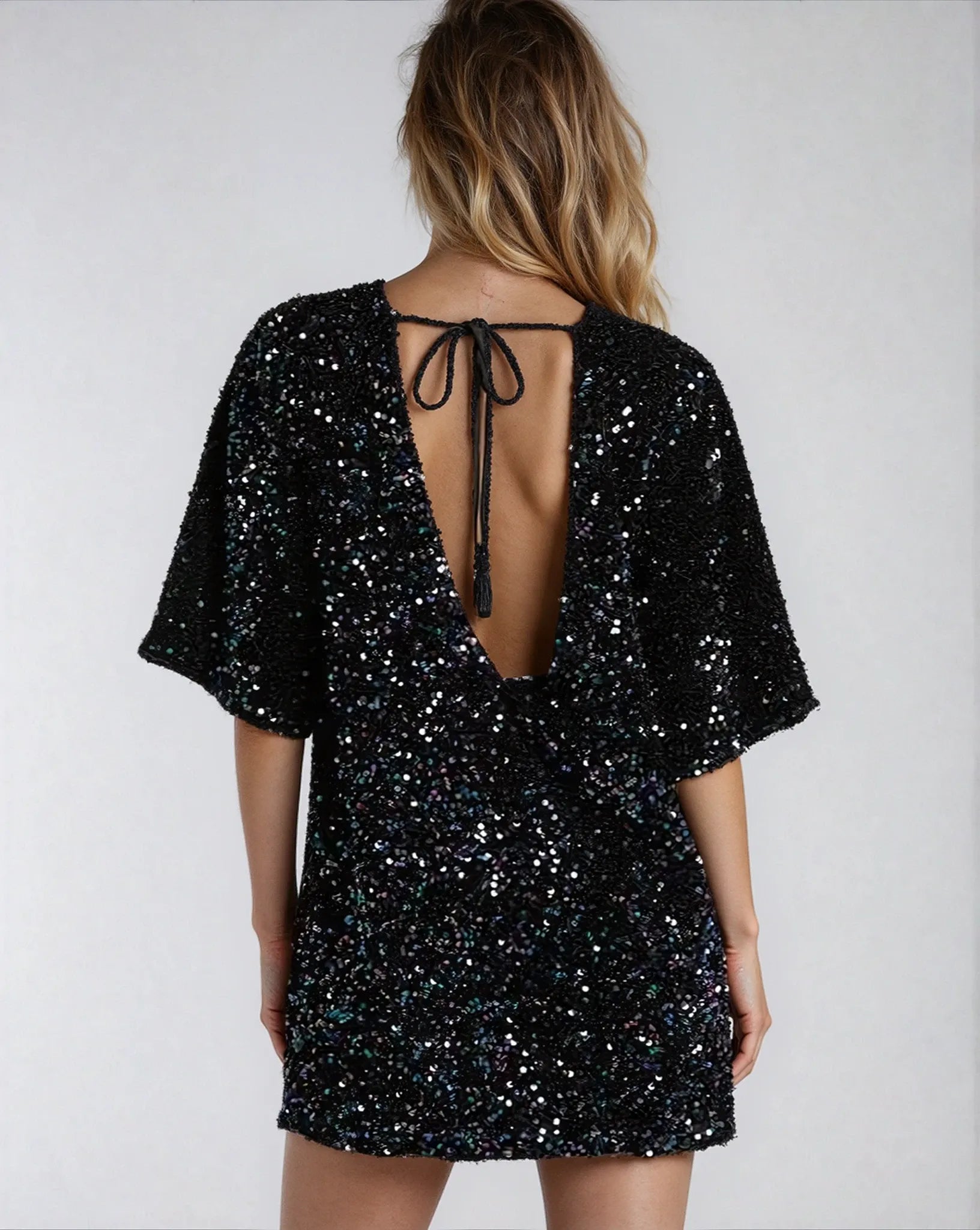 Vue arrière d'une élégante robe noire à sequins Ezia avec un dos nu et des manches en cloche étincelantes.