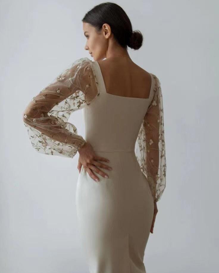 Robe blanche élégante avec manches longues transparentes ornées de fleurs pour une tenue chic et sophistiquée.