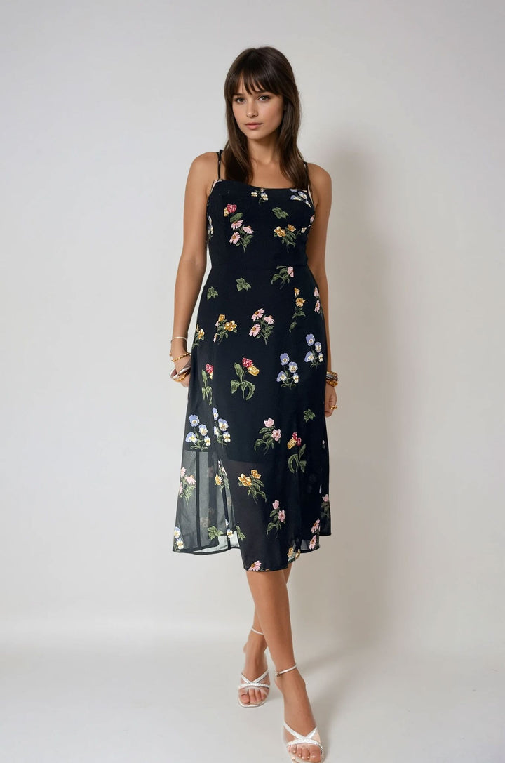 Robe longue fleurie Maria avec motif floral coloré sur fond noir, idéal pour l'été avec sa fente élégante et moderne.