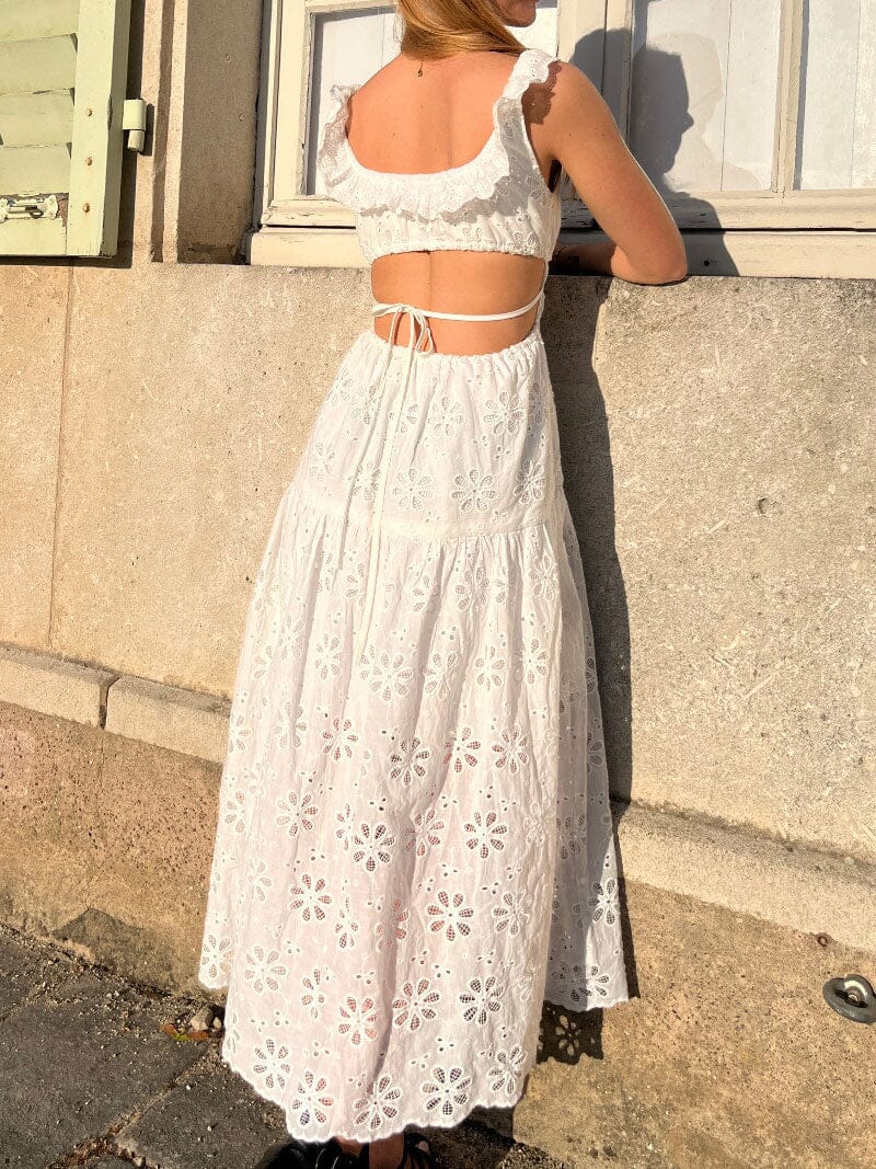 femme portant une robe blanche brodée avec des manches à volants et un dos nu
