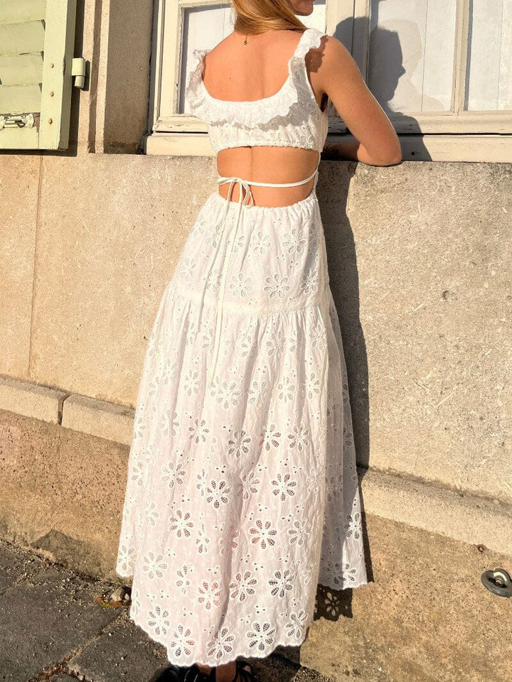 femme portant une robe blanche brodée avec des manches à volants et un dos nu