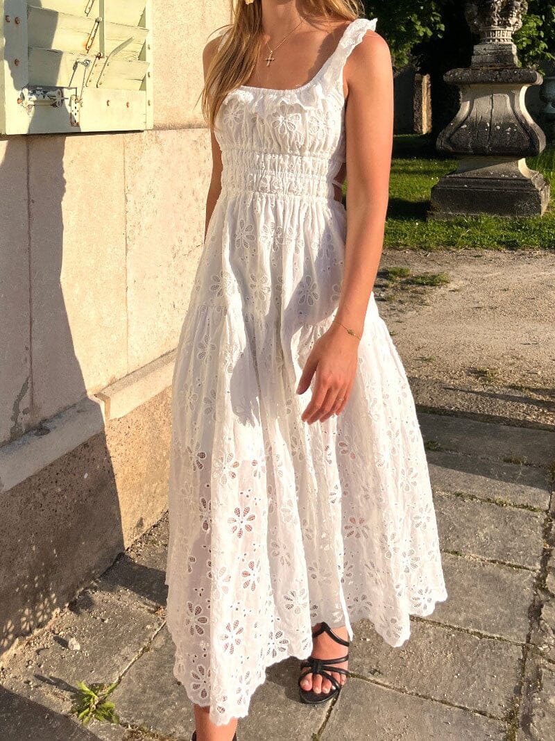 femme portant une robe blanche brodée avec des manches à volants et un dos nu