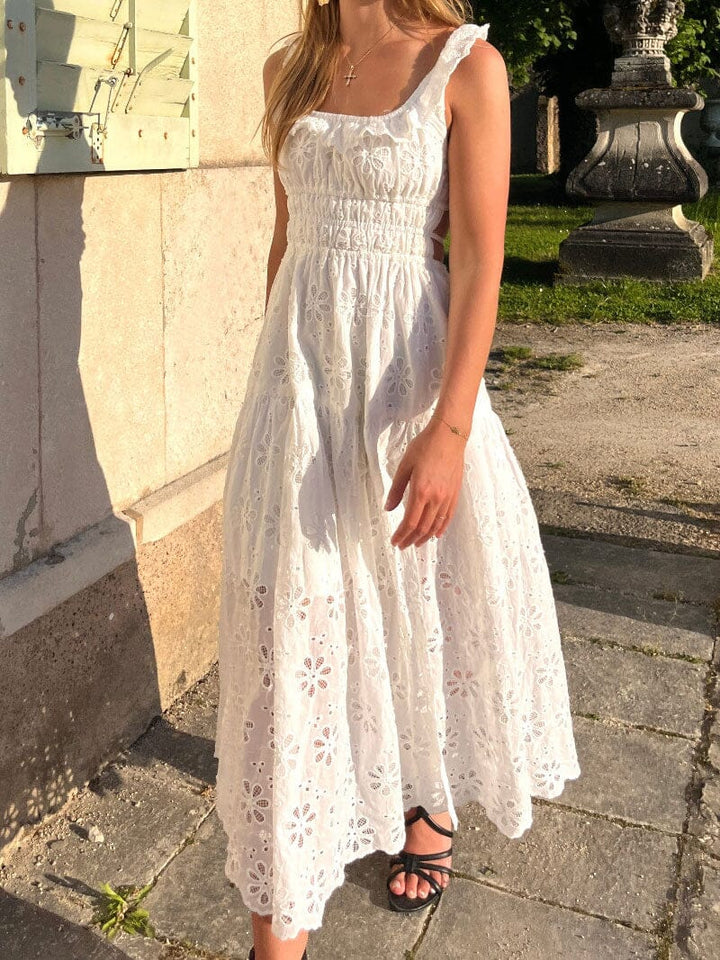 femme portant une robe blanche brodée avec des manches à volants et un dos nu