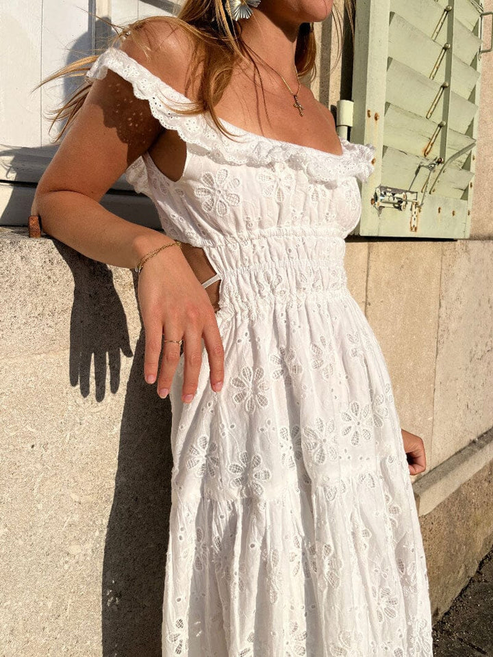 femme portant une robe blanche brodée avec des manches à volants et un dos nu