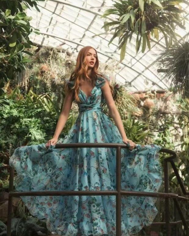 femme portant une robe longue dos nu fleurie line dans une serre botanique avec des plantes et fleurs exotiques