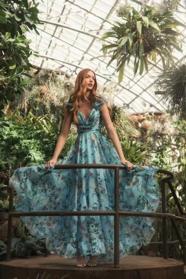 femme portant une robe longue dos nu fleurie line dans une serre botanique avec des plantes et fleurs exotiques