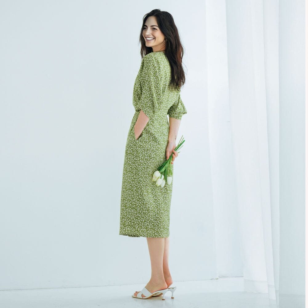 robe longue fluide fleurie verte avec des petits motifs blancs, portée par une femme de profil tenant des tulipes blanches