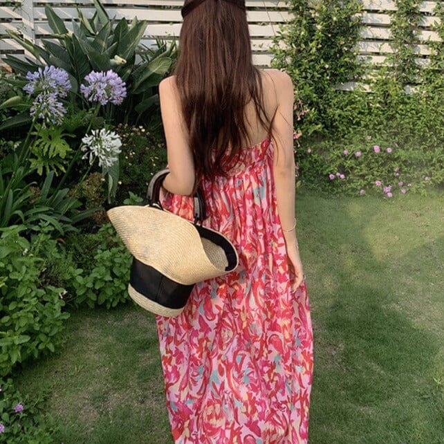 femme portant une robe longue bustier colorée dans un jardin verdoyant avec un chapeau de paille dans la main