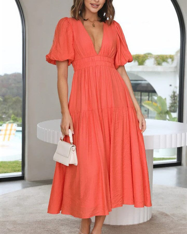 femme portant une robe décolleté plongeant de couleur corail avec manches bouffantes, parfaite pour un look chic et élégant