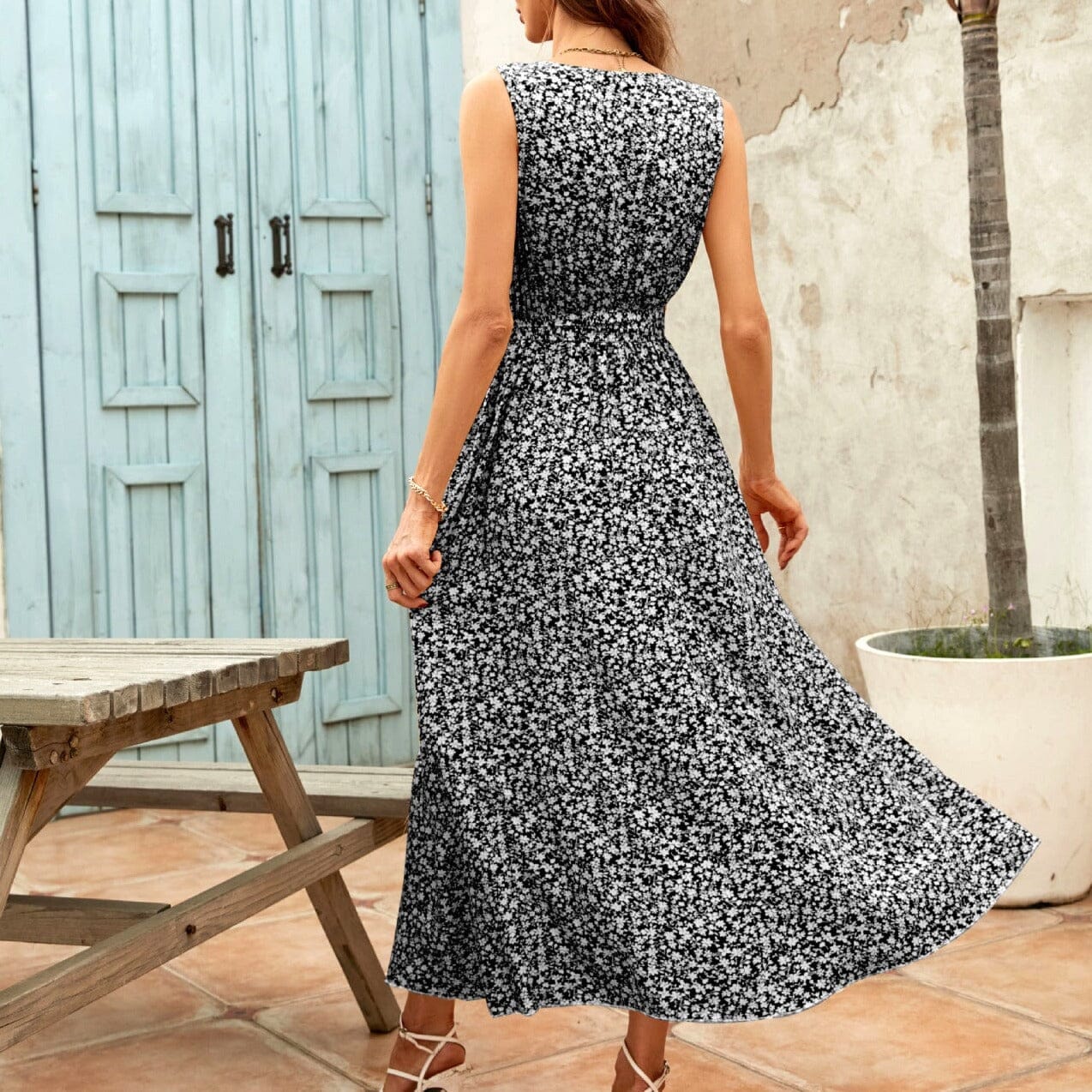 robe longue fleurie noire et blanche avec fente portant par une femme en sandales blanches, fond en terrasse extérieure