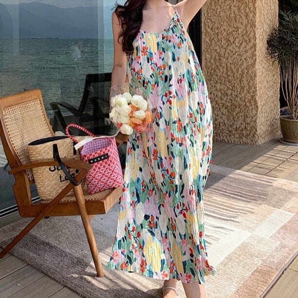 robe longue plissée lya avec motifs colorés portée par une femme devant une terrasse ensoleillée avec vue sur la mer