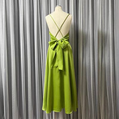 robe satin dos nu tessa mi-longue en soie vert olive avec un noeud à la taille vue de dos sur un fond à rideaux