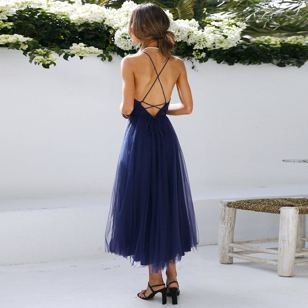 femme portant une robe longue en tulle bleue avec un dos nu croisé dans un environnement extérieur élégant