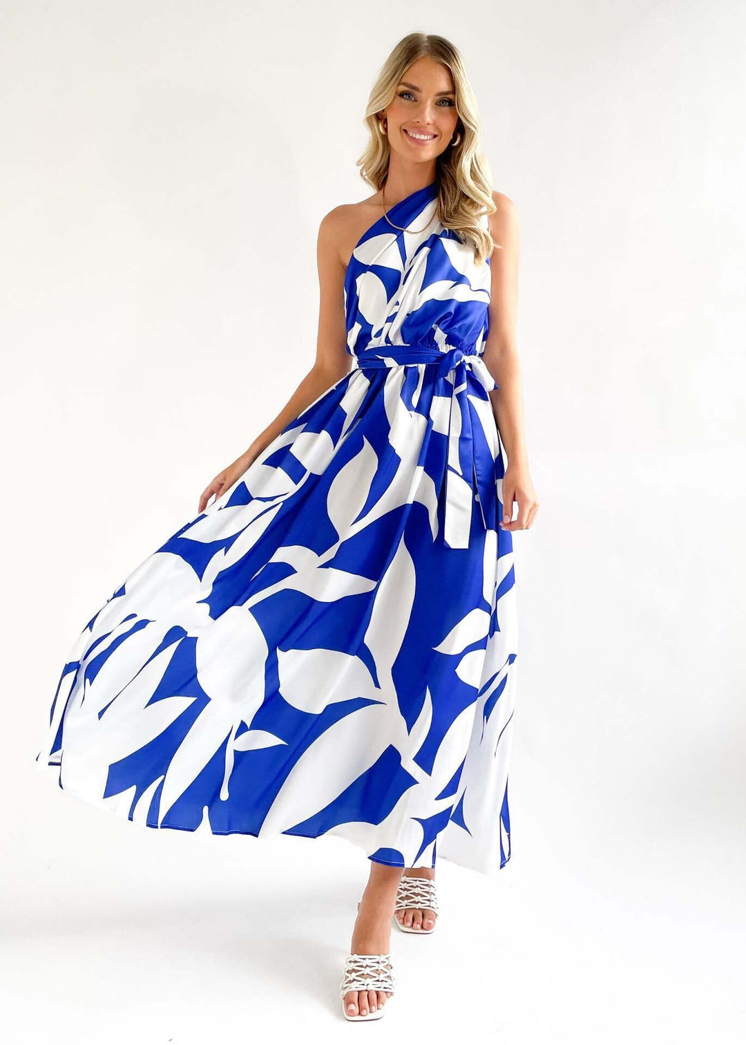 robe bleue et blanche à motif floral une épaule dénudée, femme souriante, idéale pour les occasions élégantes