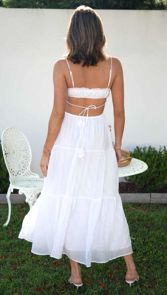 robe d'été blanche ouverte sur les côtés vue de dos portée par une femme dans un jardin