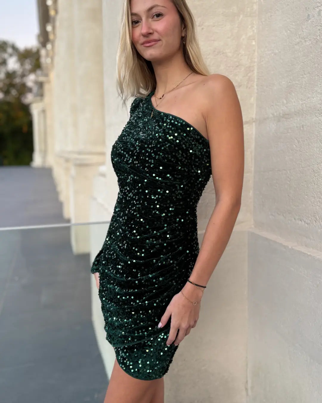 Robe courte asymétrique en paillettes noires portée par un mannequin, modèle Dorothée, idéale pour fêtes et soirées.