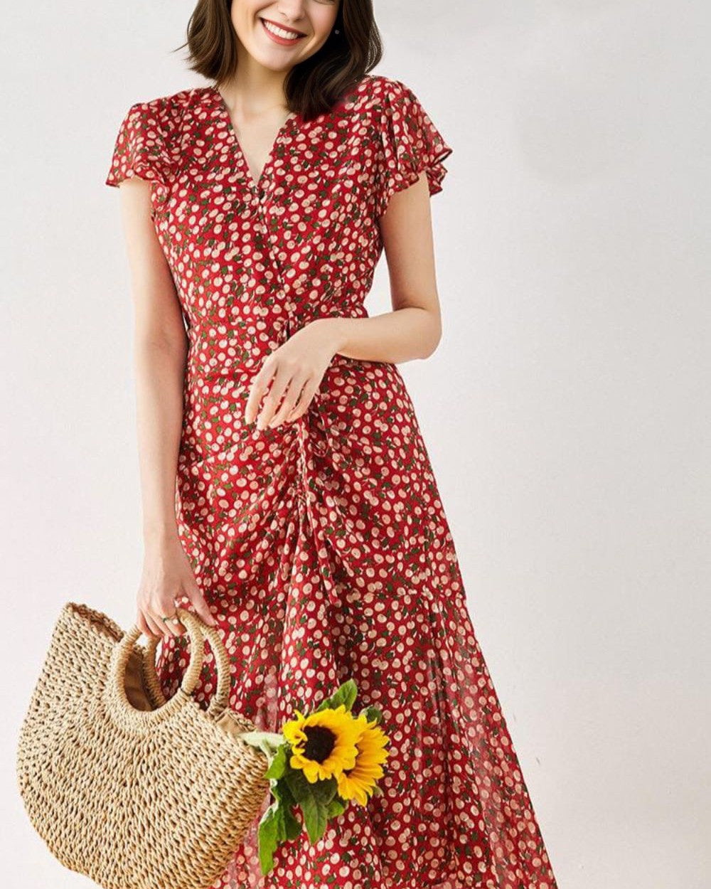 jeune femme souriante portant une robe longue rouge avec un motif à pois et tenant un sac en osier avec un tournesol