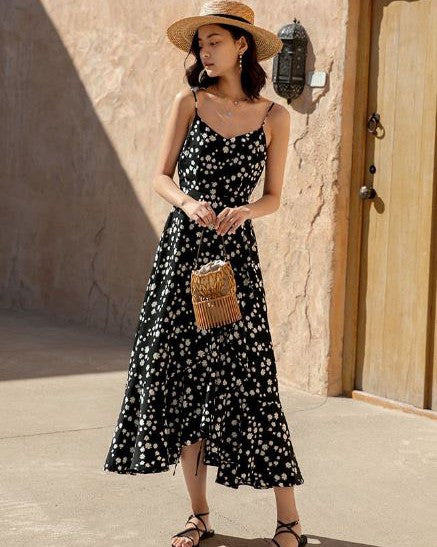 robe longue à fleurs noire aliénor pour été avec bretelles fines et chapeau de paille, et une femme en extérieur