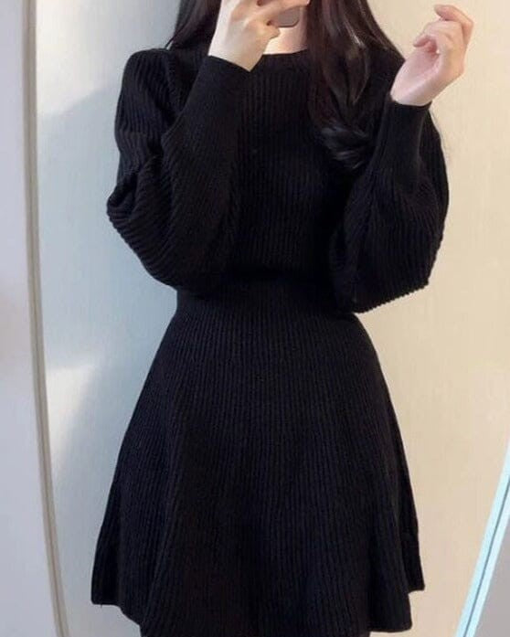 Robe pull courte en maille noire avec manches longues et col rond, ajustée à la taille, modèle Mira pour femme.