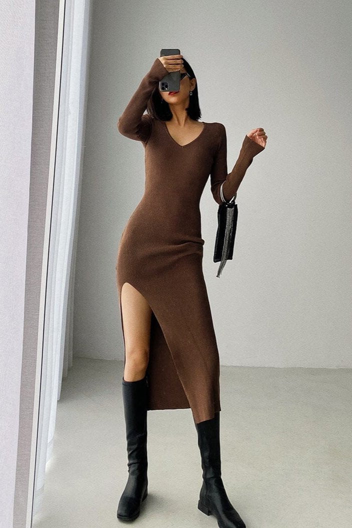 Femme portant une élégante robe pull longue marron avec fente, style moderne, parfaite pour l'automne et l'hiver.