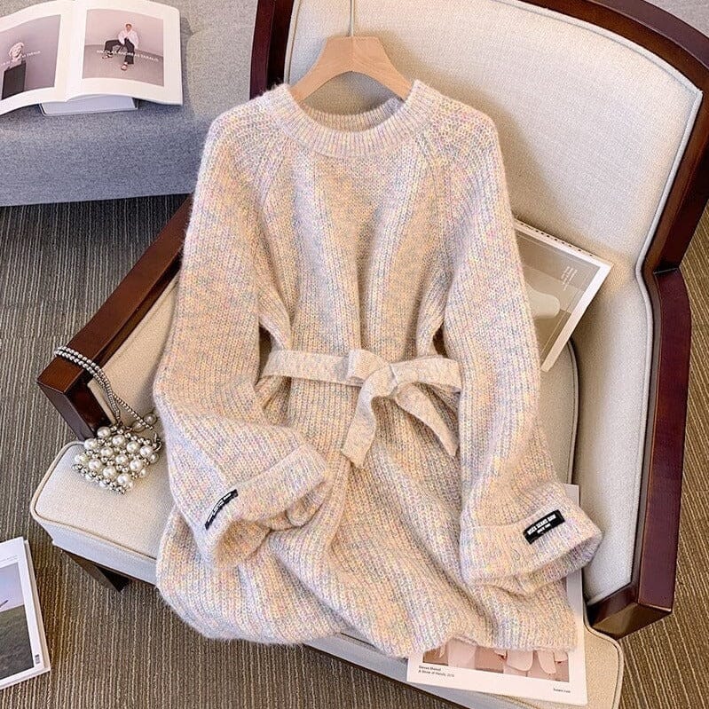 robe pull avec ceinture romane posée sur un fauteuil beige avec des magazines ouverts en arrière-plan