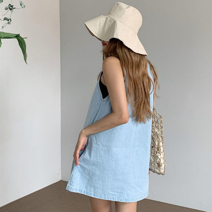 femme portant une robe en jean courte jordana de dos avec un grand chapeau beige et un sac à main en raphia