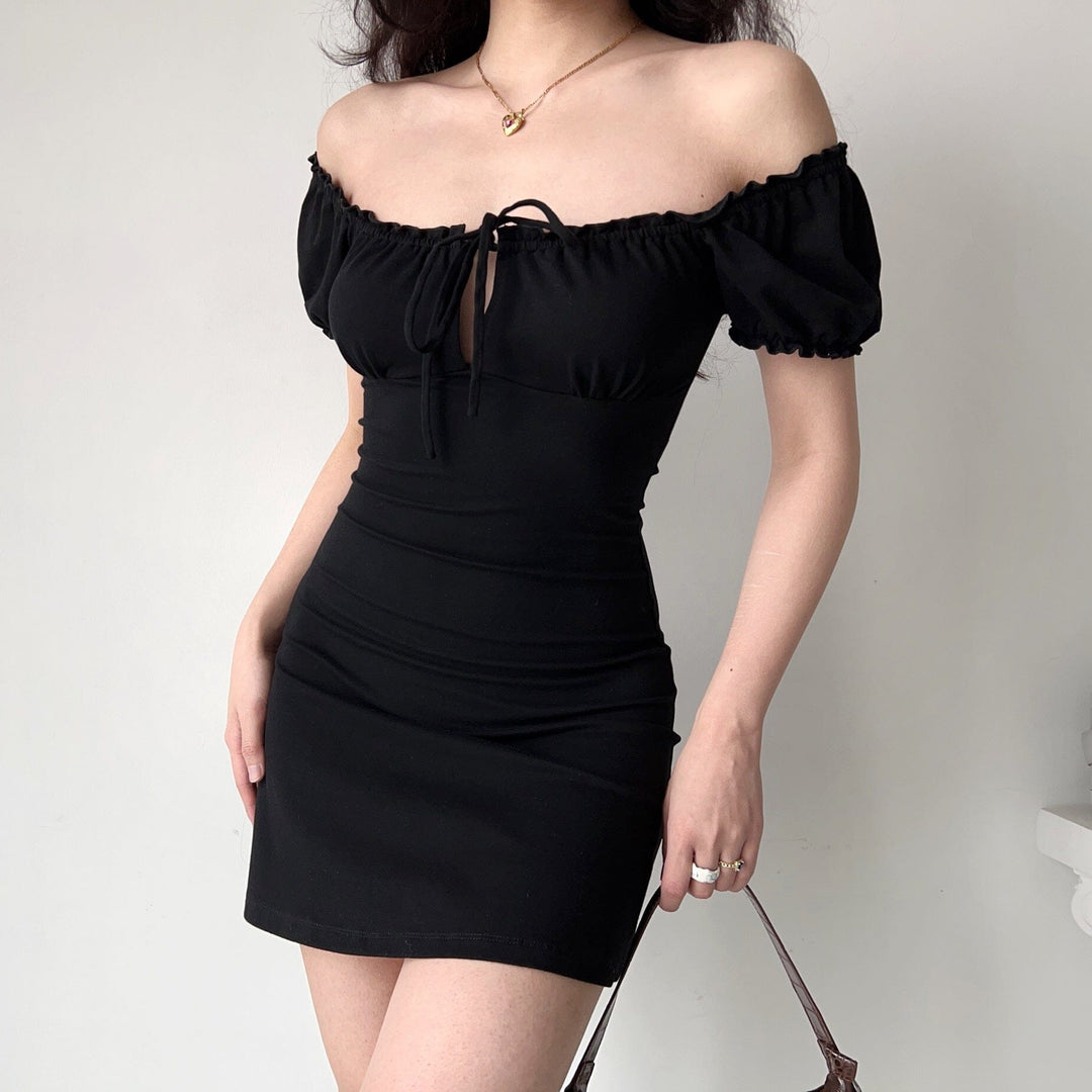 Robe noire courte avec manches bouffantes portée par une femme, idéale pour une soirée élégante ou une sortie décontractée.