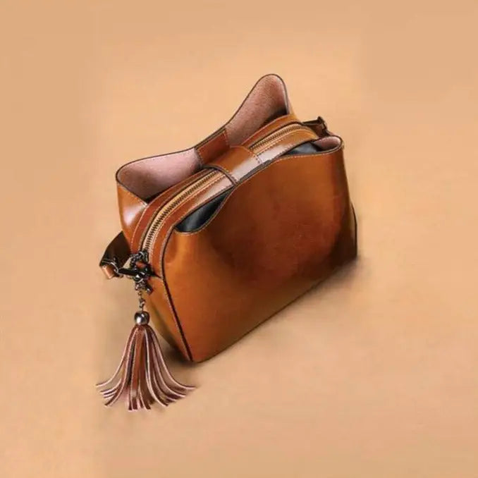 petit sac bandoulière en cuir marron avec pompon en décoration, idéal pour un usage quotidien et sorties élégantes