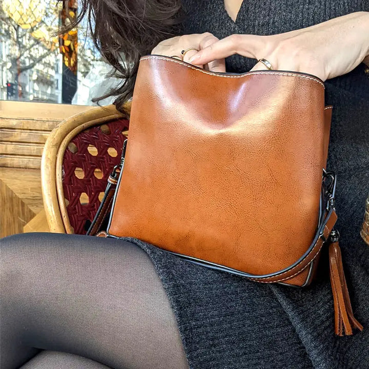 femme avec petit sac bandoulière cuir marron enzo, assise dans un café, parfait accessoire mode élégant et pratique