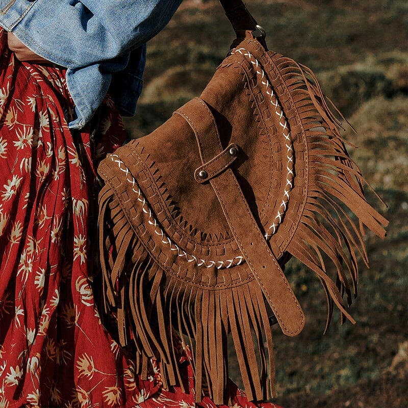 sac en daim à frange marron porté avec une robe fleurie et une veste en jean pour un look bohème chic en extérieur