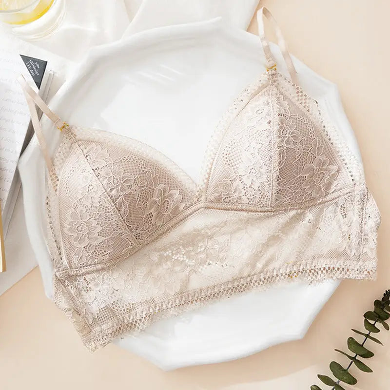 soutien-gorge dos nu invisible camélia en dentelle beige délicate, posé sur une assiette blanche avec une feuille verte