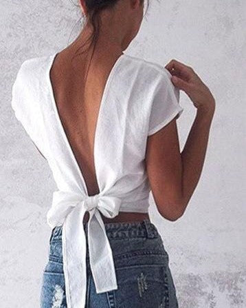 Femme portant un haut blanc dos nu style bohème avec un nœud, idéal pour mettre en valeur un soutien-gorge chic.