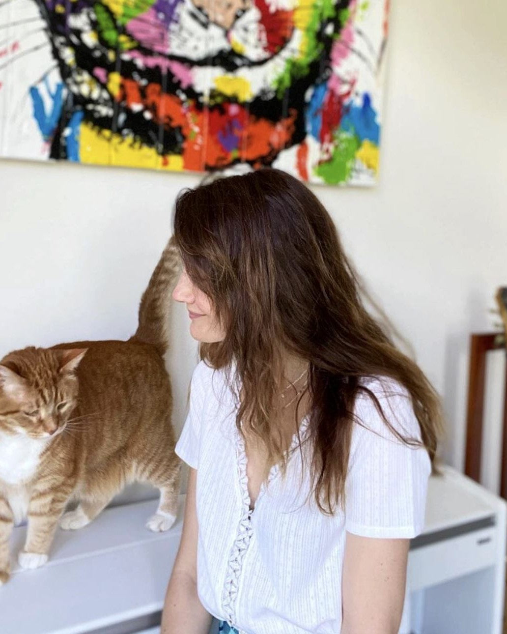 femme portant un t-shirt en coton saki édition limitée avec un chat orange devant un tableau coloré