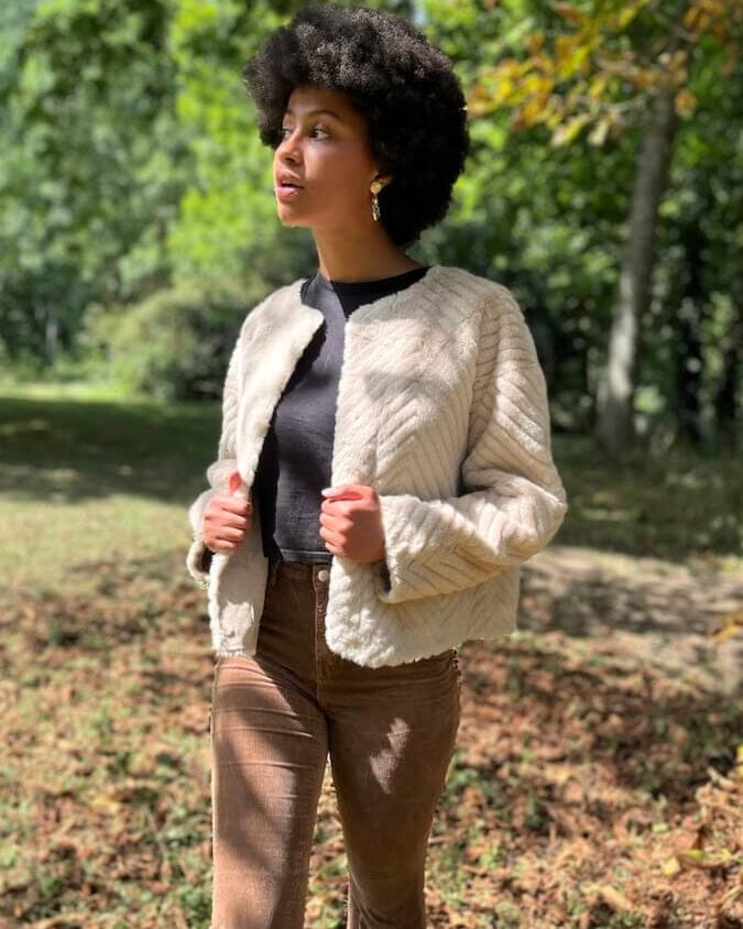 Femme portant une élégante veste en fausse fourrure chic, modèle Marcella, dans un environnement naturel automnal.