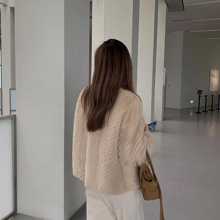 veste femme fausse fourrure chic beige pour un look élégant et moderne en intérieur lumineux avec pantalon blanc et sac marron