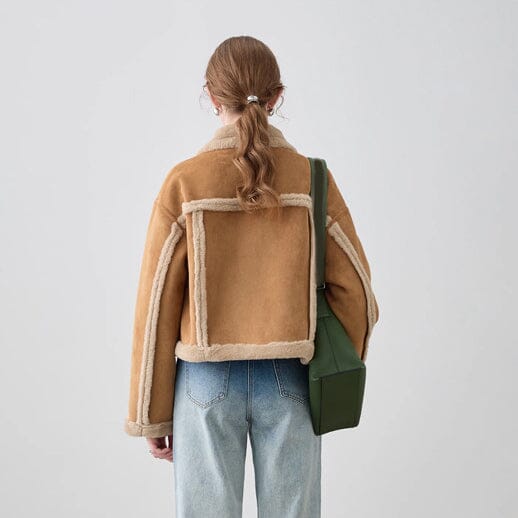 Une femme porte un blouson fourré beige en étant vue de dos, avec un sac vert sur l'épaule, adaptée pour un look hivernal.