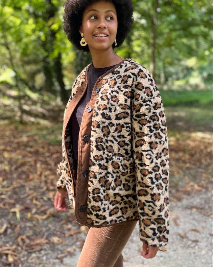 Jeune femme souriante portant une élégante veste en polaire à motif léopard, idéale pour un style audacieux et chic.