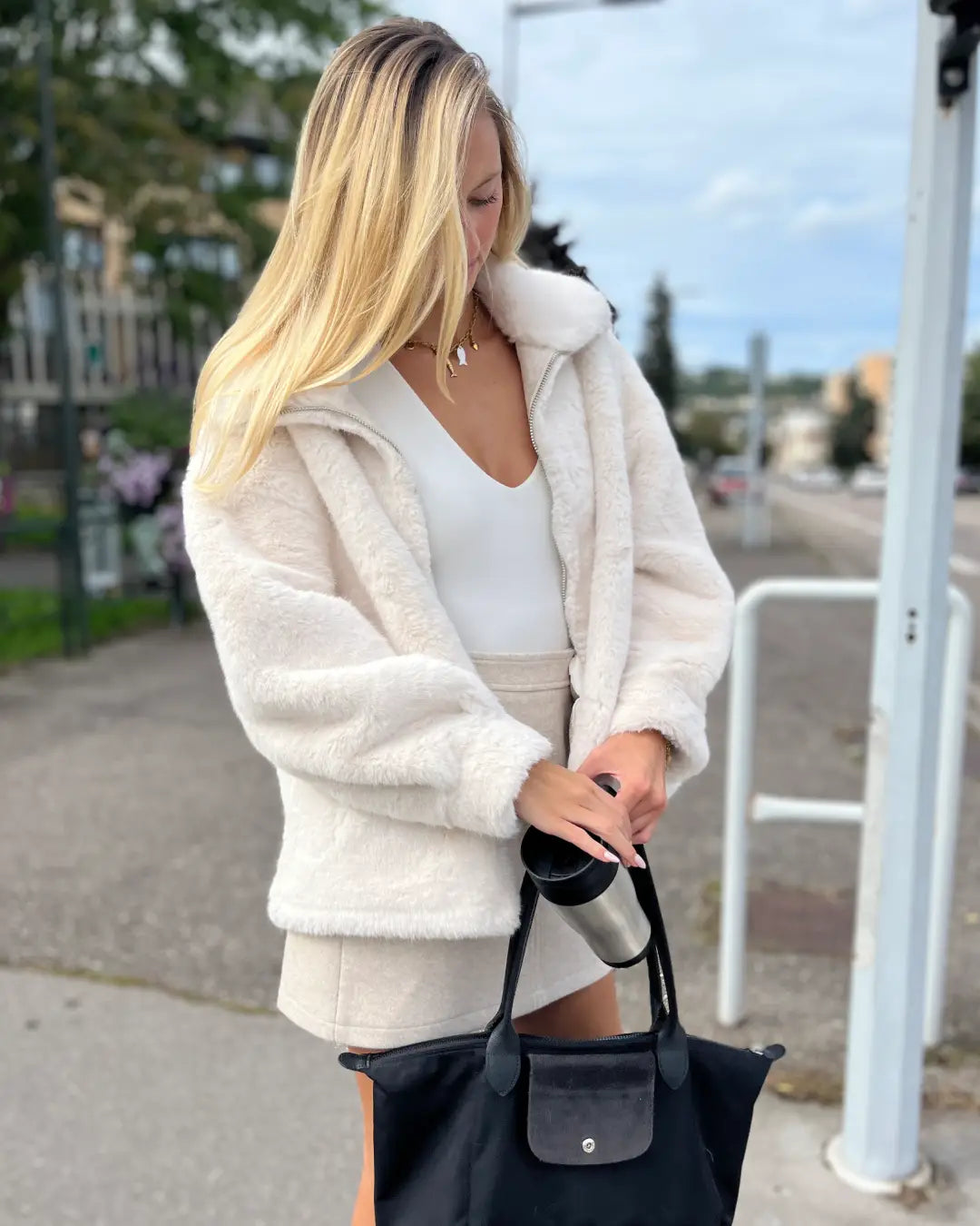 Veste en fausse fourrure blanche élégante pour femmes, parfait pour les journées fraîches d'automne en ville.