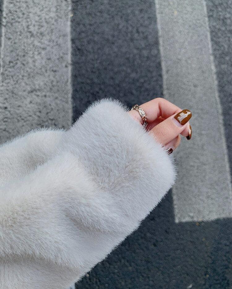 détail de la manche d'une veste en fausse fourrure femme, main avec bague en argent, élégance féminine et mode automne-hiver