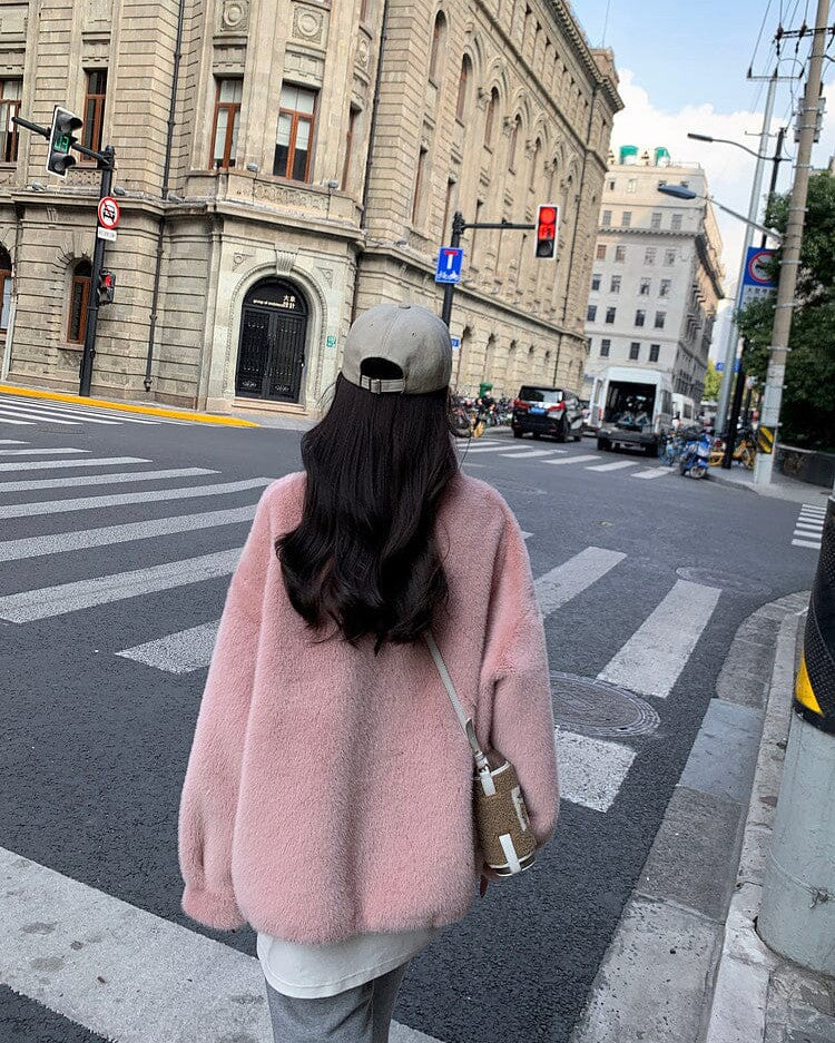 veste en fausse fourrure rose pour femme, modèle julia, vue de dos en pleine rue urbaine avec des bâtiments historiques