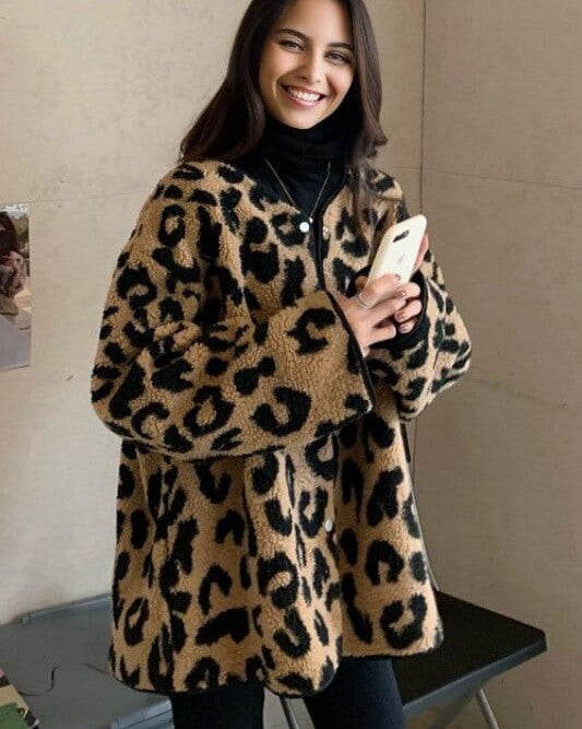 Femme souriante portant une veste en sherpa motif léopard, confort et style moderne pour temps frais.