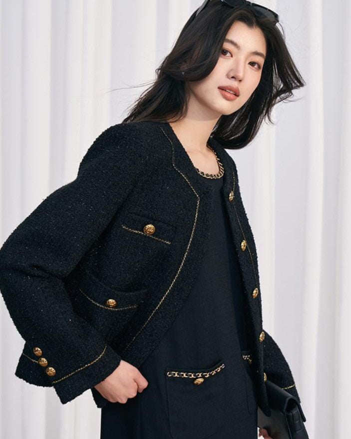 veste chic et classique gabriella en tweed noir, portée par une femme élégante avec un sac à main noir et des lunettes de soleil