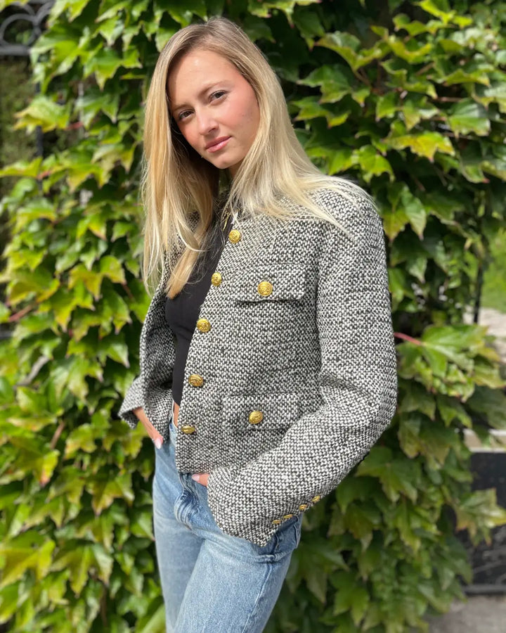 Veste en tweed pour femme avec boutons dorés, portée en extérieur, parfaite pour un look élégant et décontracté.