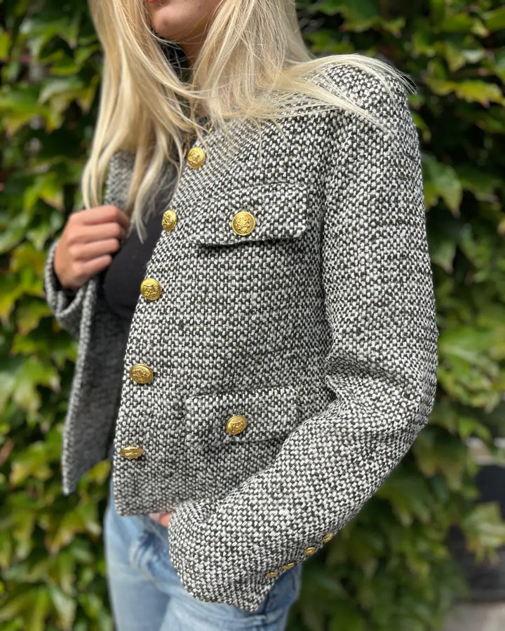 Veste en tweed grise pour femme avec boutons dorés, élégante et intemporelle, idéale pour un style chic décontracté.
