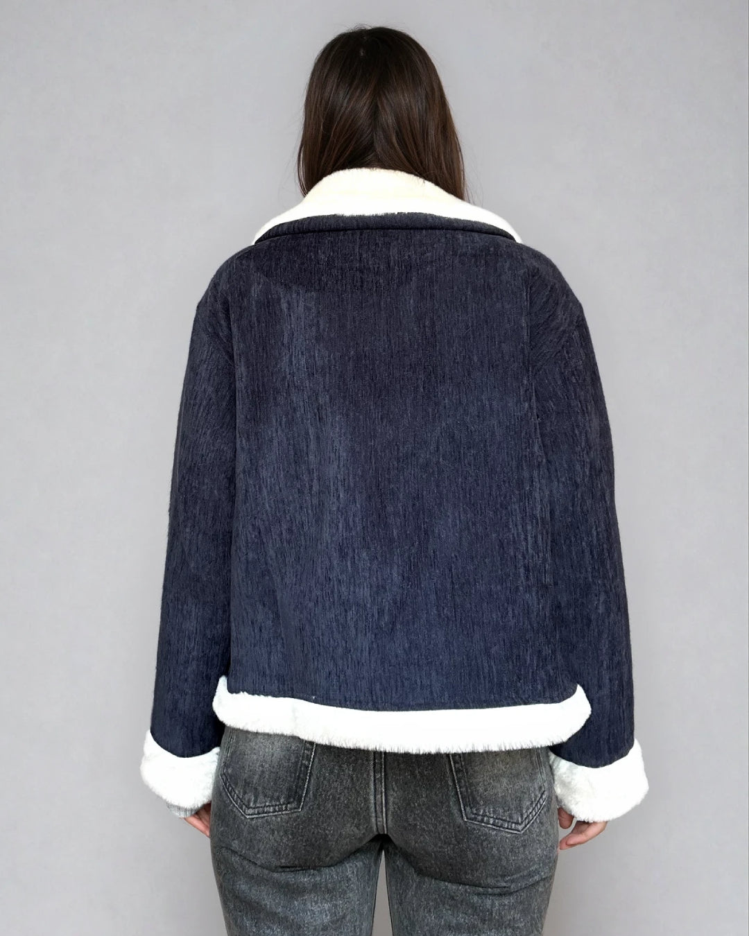 Veste en velours bleu avec doublure en fausse fourrure blanche portée par une femme vue de dos, modèle Camille élégant.