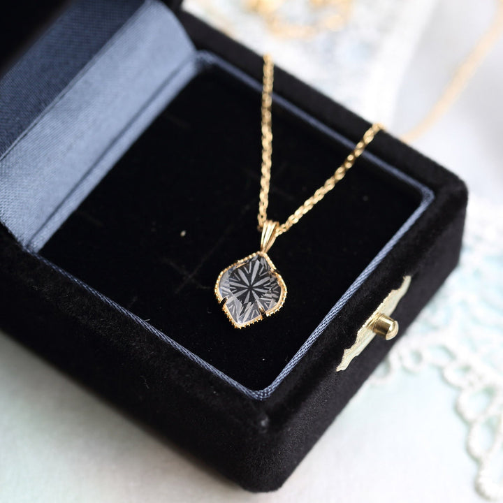 collier pendentif losange en cristal alina en or dans un écrin noir. élégant bijou en cristal taillé pour femmes