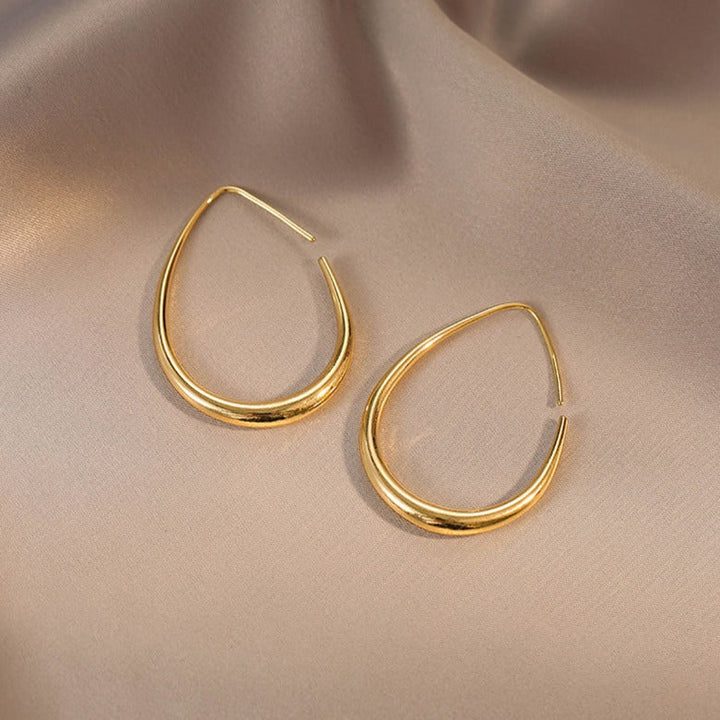 anneaux dorés créoles élégants en forme de goutte sur un tissu soyeux, bijou doré chic pour femmes modernes